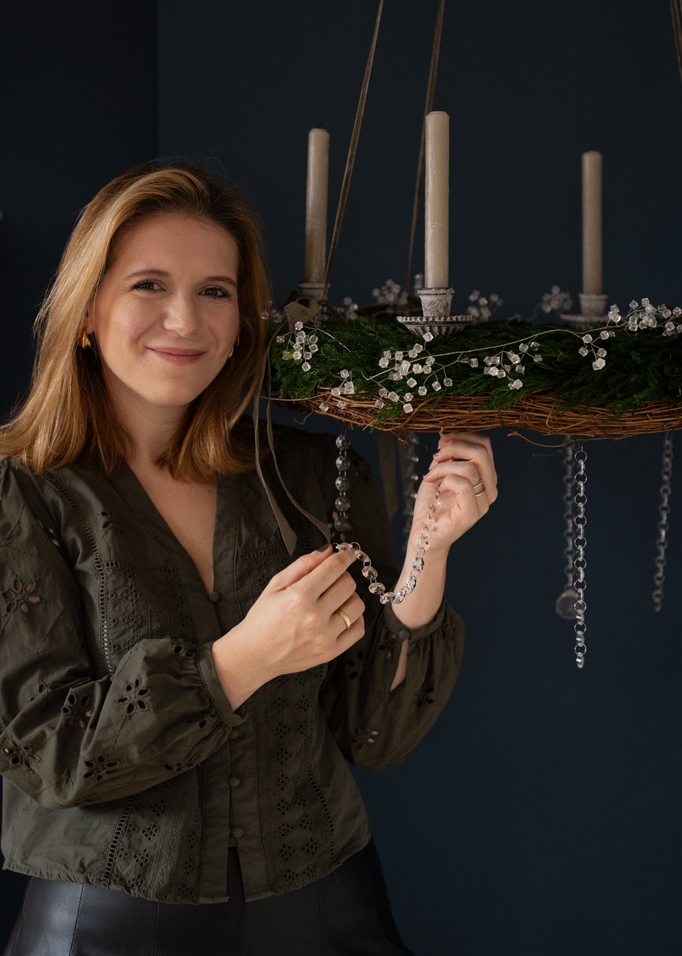 Grüner Adventskranz mit weißen Kerzen und Kristall-Dekorationen, hängend an Bändern