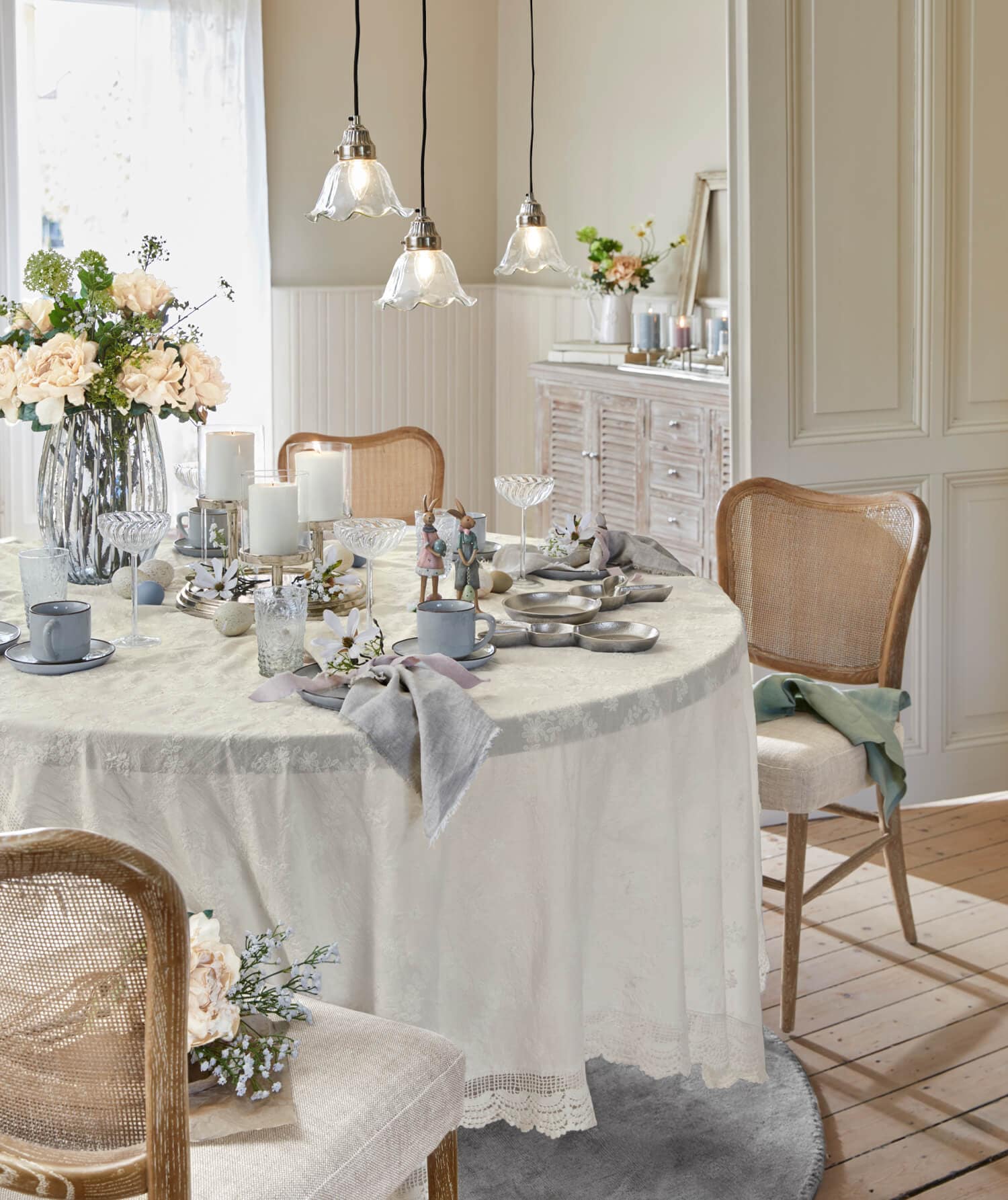 Heller Esstisch mit cremefarbenem Tischdecke und rustikaler Dekoration, Holzstühle und Blumen im Esszimmer