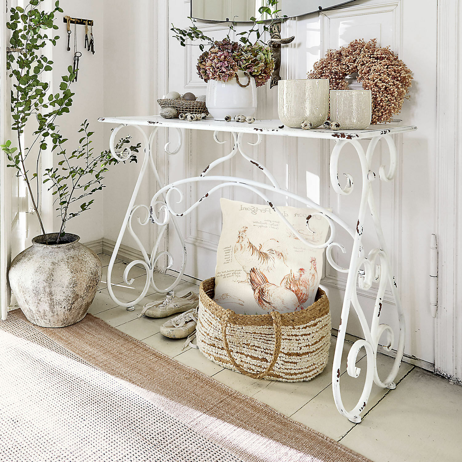Konsole Stonem Weißer Metalltisch mit dekorativen Pflanzen und Korb mit Kissen im rustikalen Stil