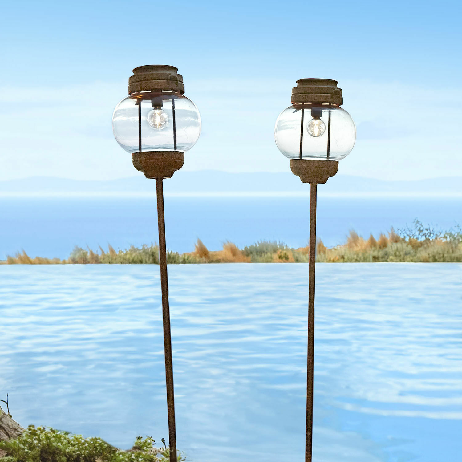Solar-Laterne 2er Set Nayalif Zwei Gartenlaternen aus Glas und rostigem Metall am Pool mit Meerblick
