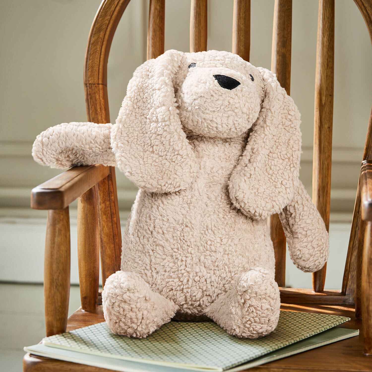 Kuschelweicher Plüschhase in Cremefarbe aus weichem Material auf Holzstuhl, Kinderdeko