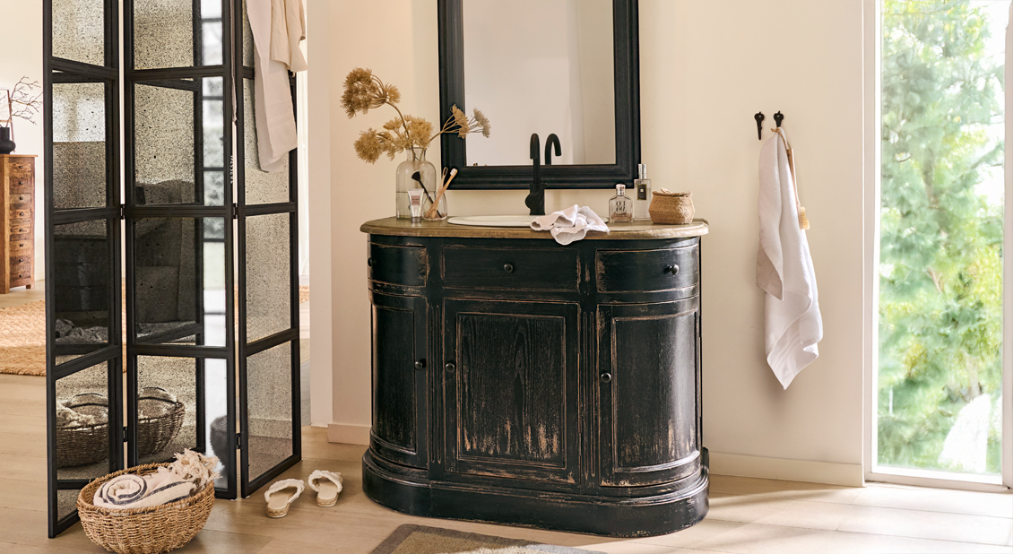 Schwarzer Holz-Badezimmerschrank mit Waschbecken und Spiegel in hellem, natürlichem Raum