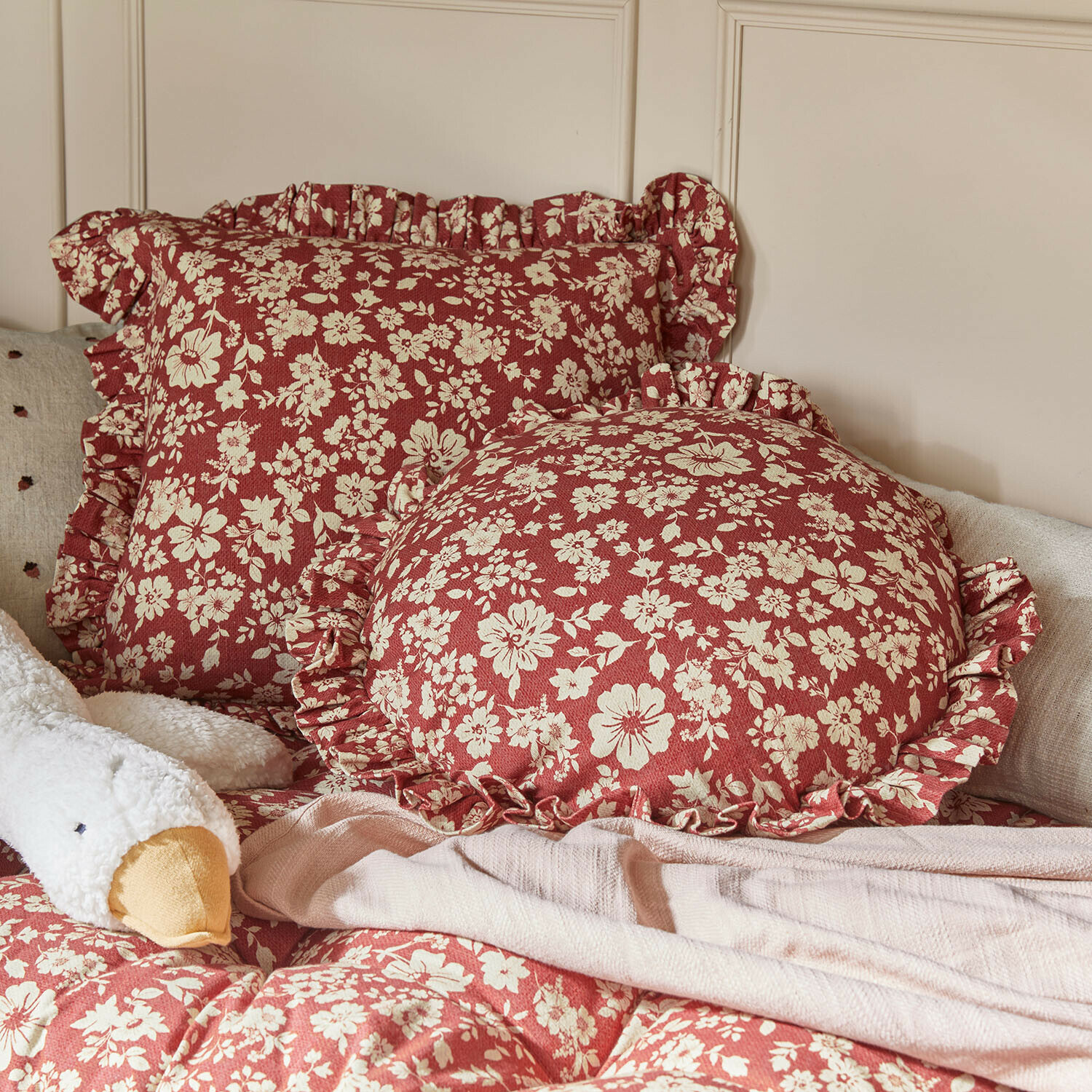 Kissen 2er Set Frambelle Rote Dekokissen mit cremefarbenem Blumenmuster und Rüschen auf Bett mit weicher Decke