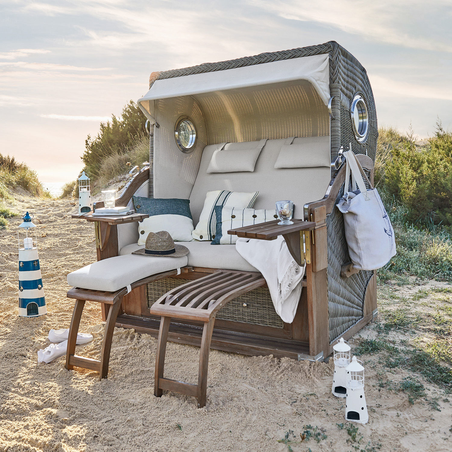 Strandkorb Clifford Beach Strandkorb aus Geflecht mit beigem Polster und Holz-Fußstützen im Sand, Gartenmöbel
