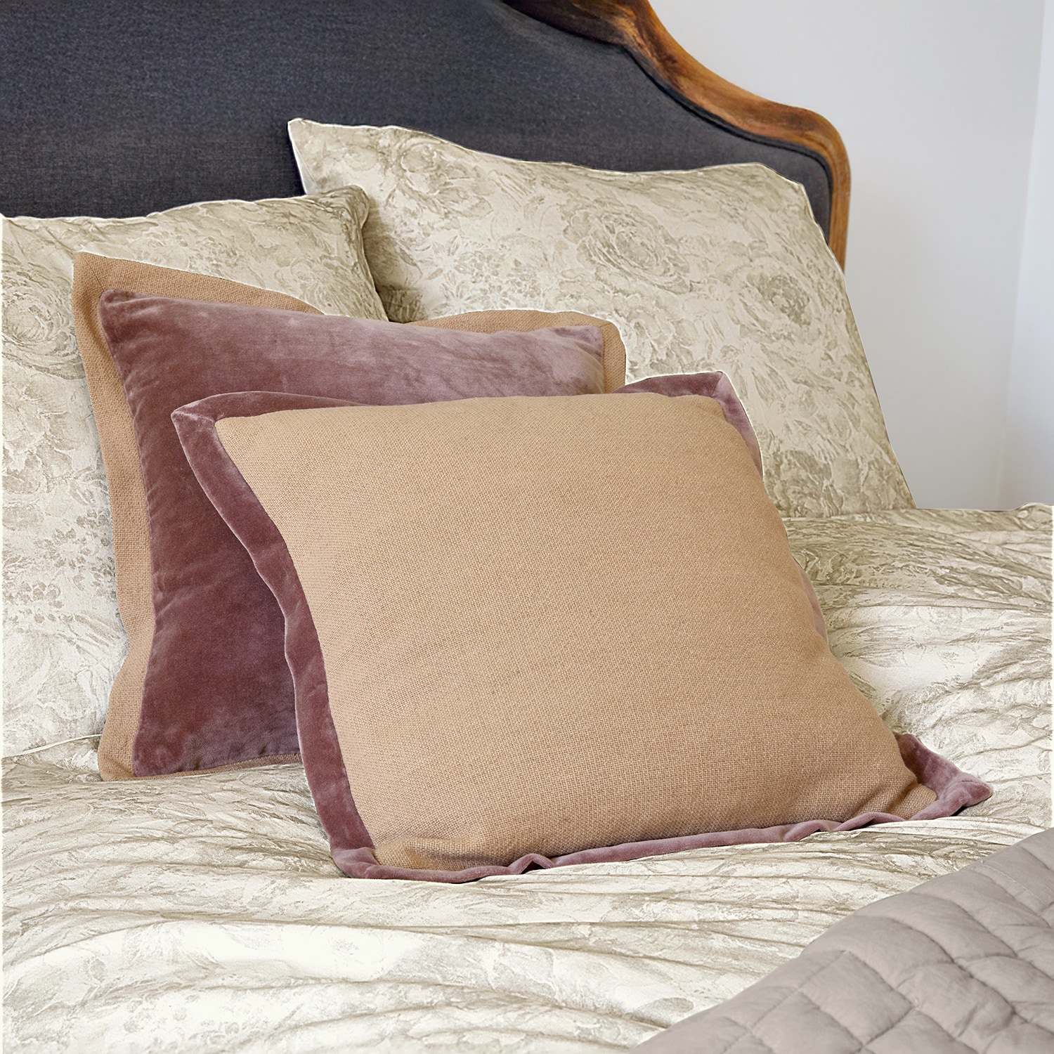 Beige und rosa Dekokissen aus Samt und Stoff auf Bett mit hellem Bettbezug