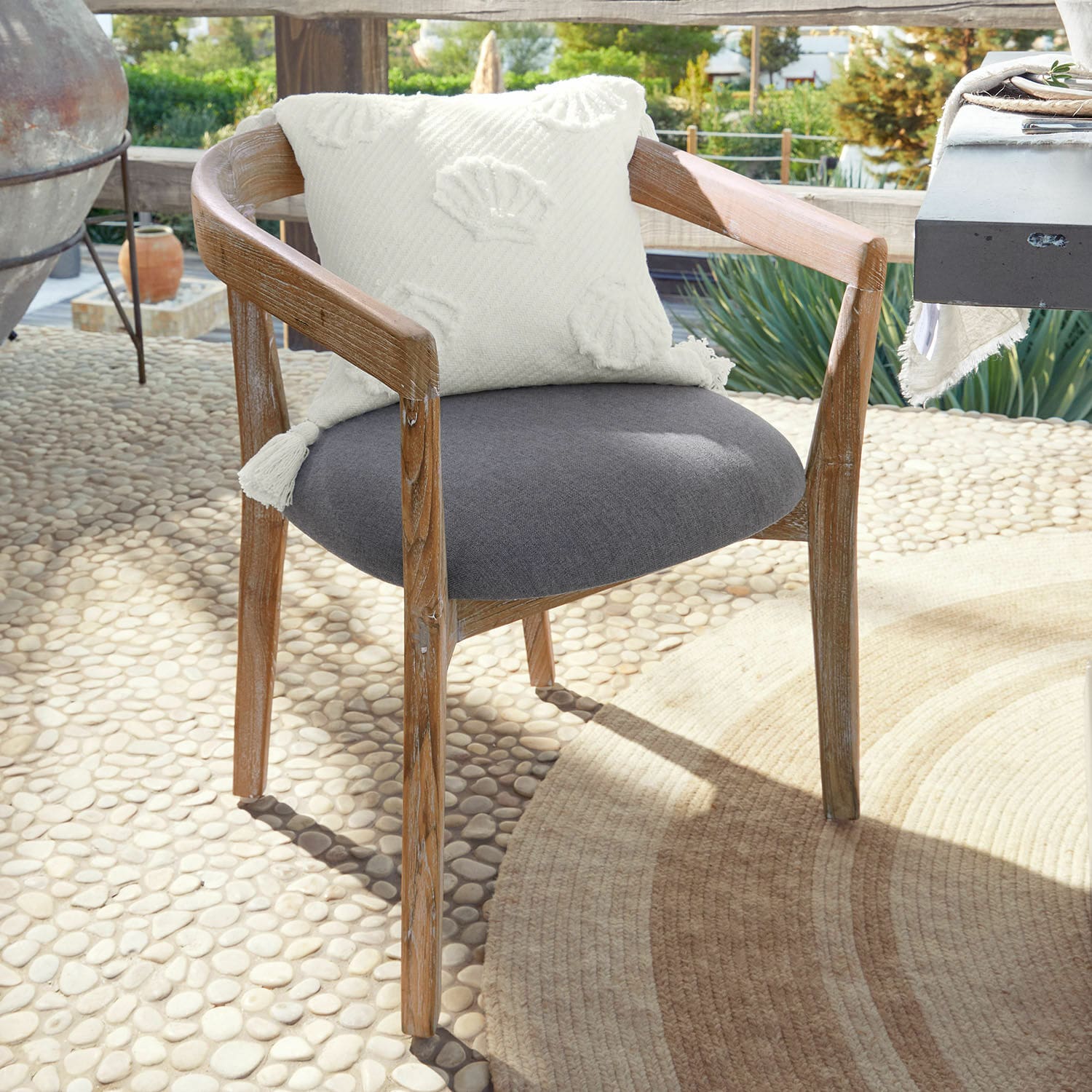 Stuhl Lunebois Stuhl aus Holz mit grauem Polstersitz und weißem Dekokissen auf sonniger Terrasse