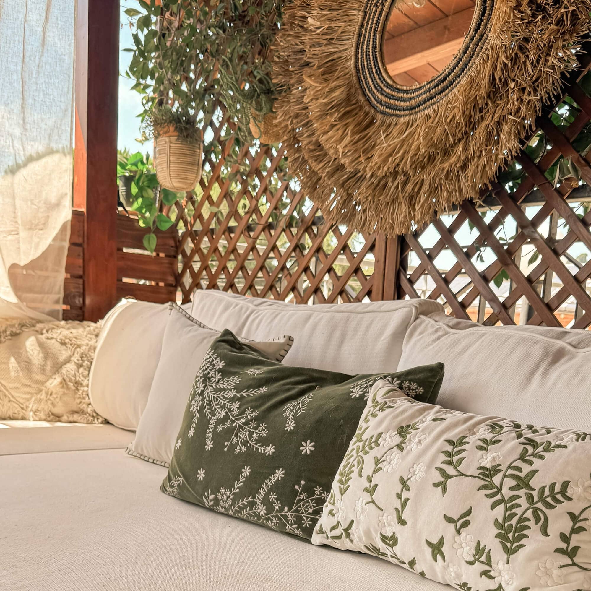 Gemütliches Sofa mit cremefarbenen und grünen bestickten Kissen in natürlichem Ambiente