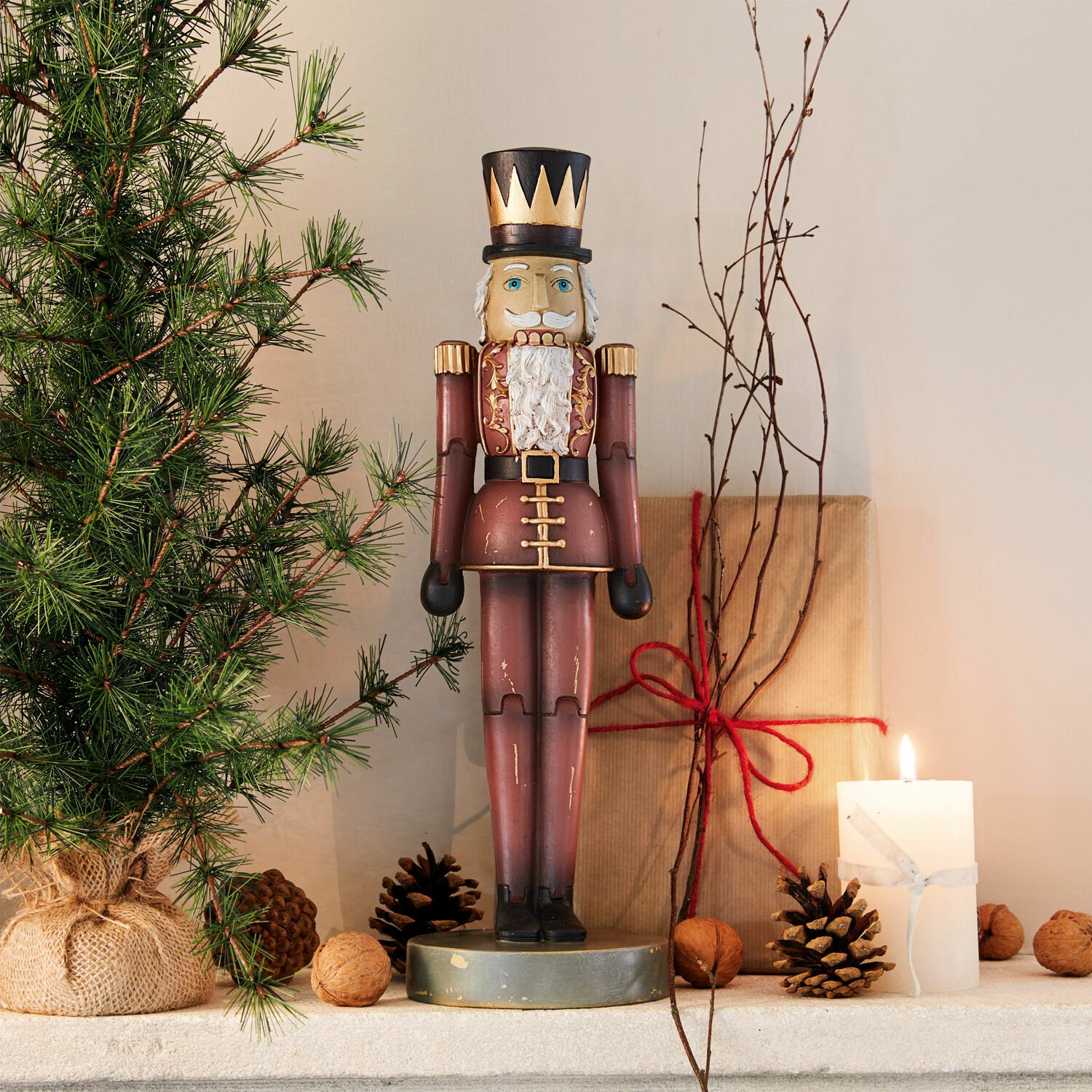 Deko-Nussknacker Serifa Holz-Nussknacker in bordeauxrotem Uniform mit schwarzem Hut, Weihnachtsdeko mit Tannenzweig und Kerze