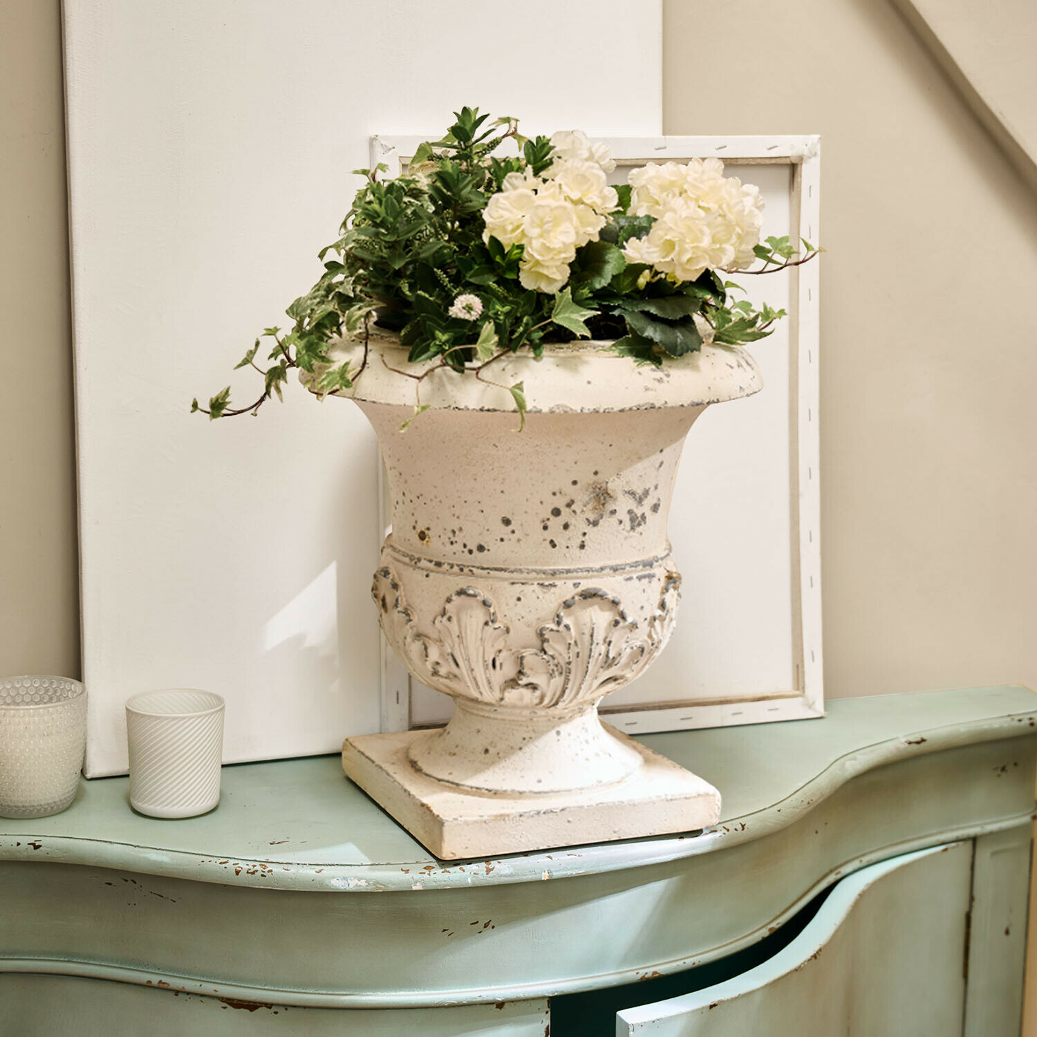 Amphore Lorianza Weißer Keramikvase mit Pflanzenarrangement auf grünem, antik wirkendem Vintage-Kommode