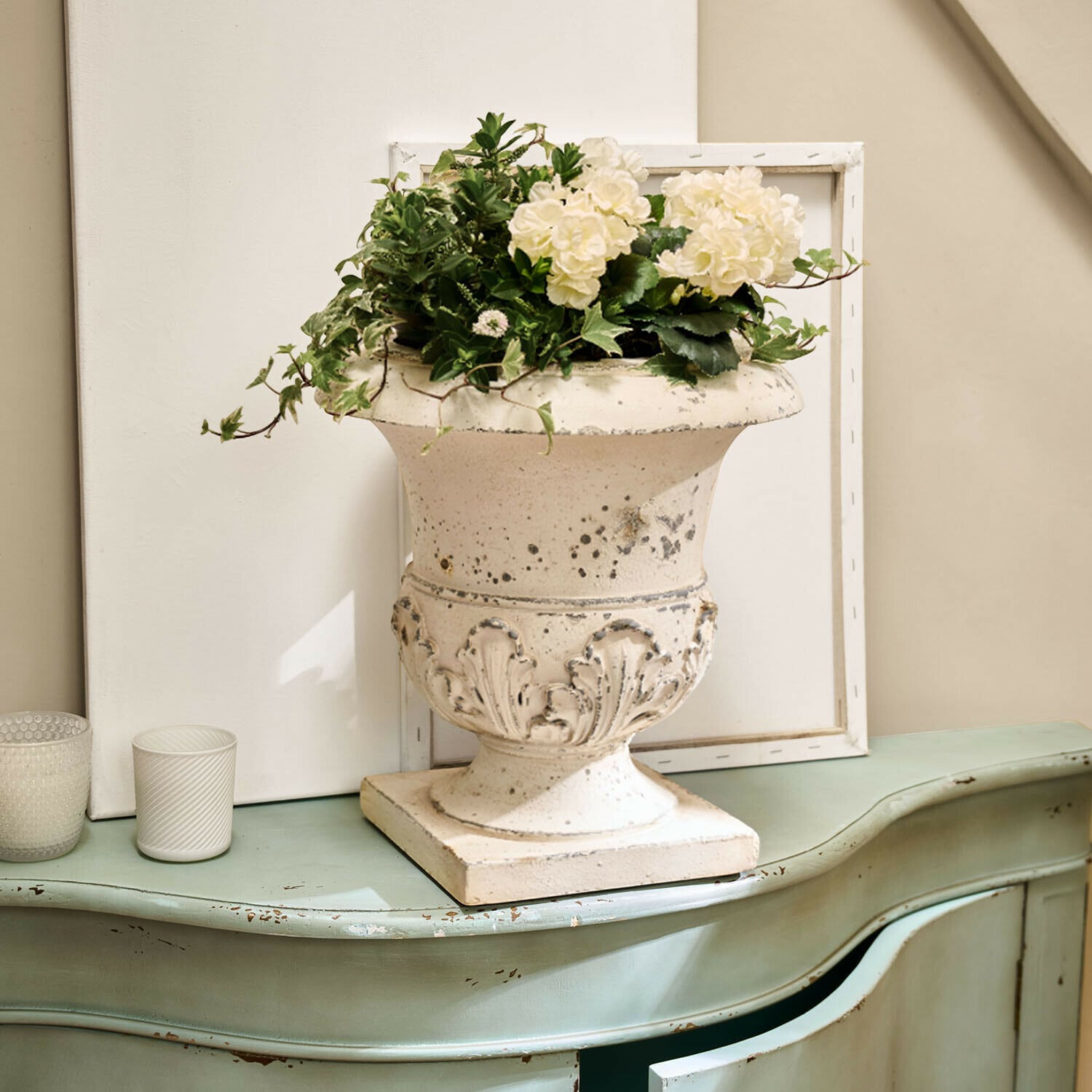 Amphore Lorianza Weißer Keramikvase mit Pflanzenarrangement auf grünem, antik wirkendem Vintage-Kommode