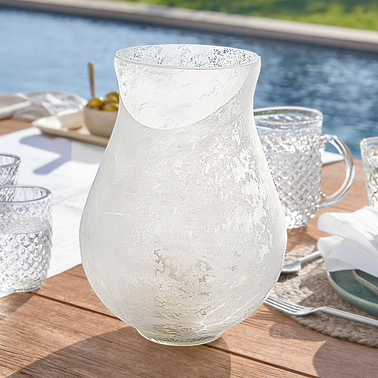 Windlicht Nareli Transparenter Krug aus mattiertem Glas auf Holztisch am Pool, stilvolles Trinkgefäß