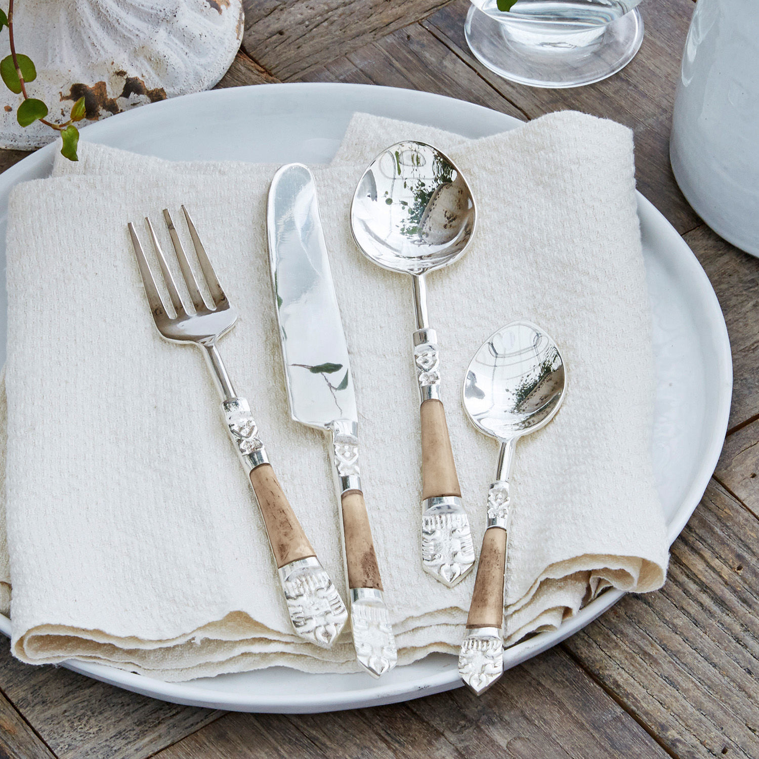 Besteck 4er Set Ferrette Besteckset mit Metallköpfen und Holzgriffen auf weißem Teller mit Leinenserviette