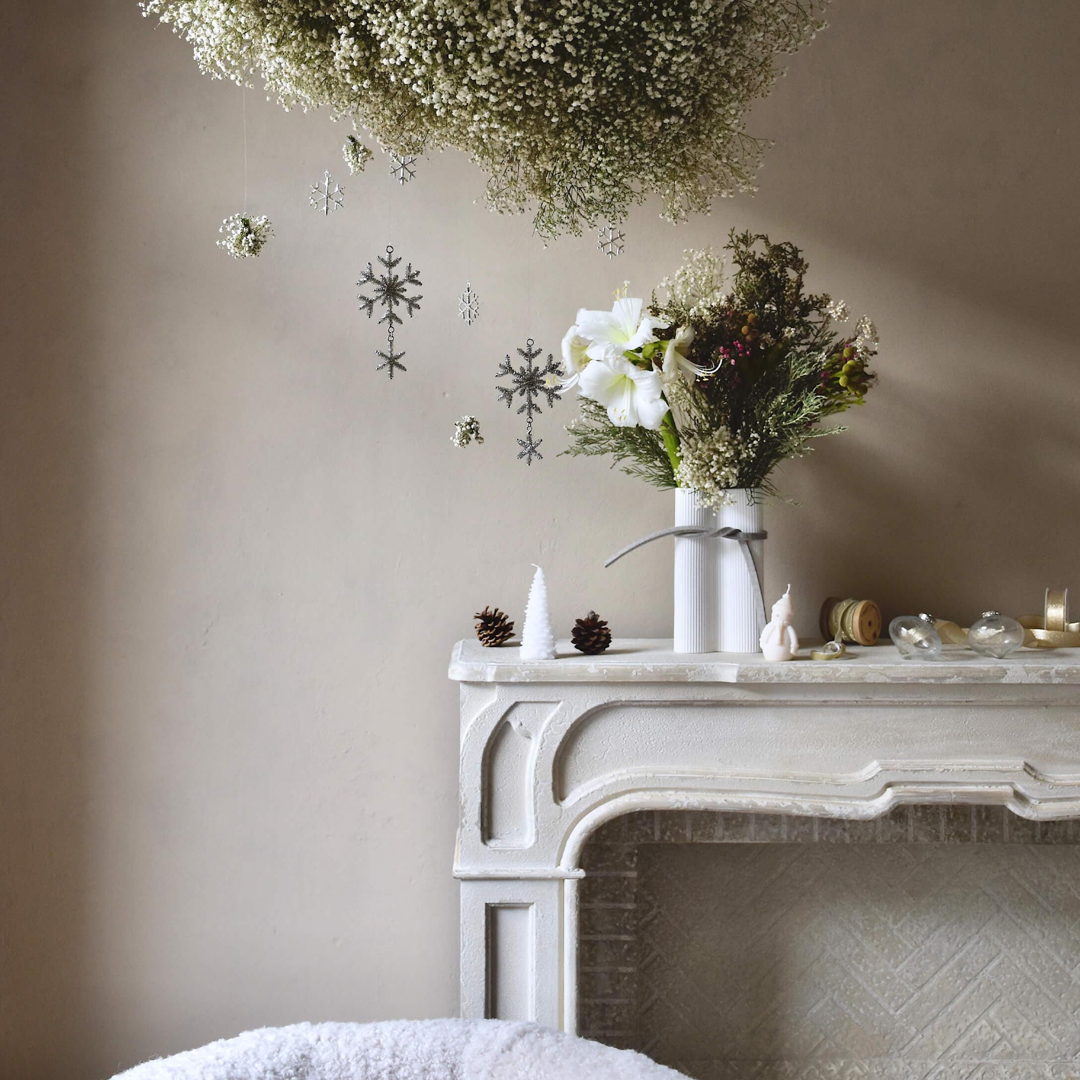 Weißer dekorativer Kamin mit Vase und Blumen, Weihnachtsdekoration mit Zapfen und Kerzen