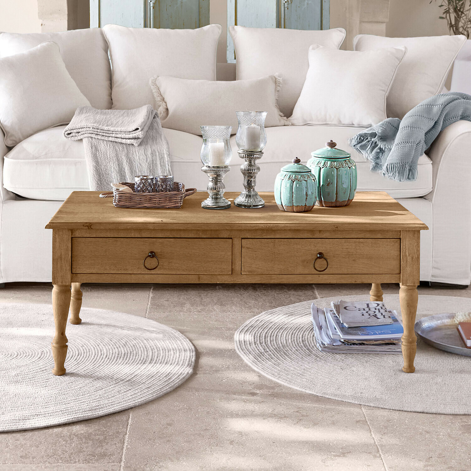 Couchtisch Rorinas Holz-Couchtisch mit Schubladen vor hellem Sofa, dekorative Kerzen und Decken darauf