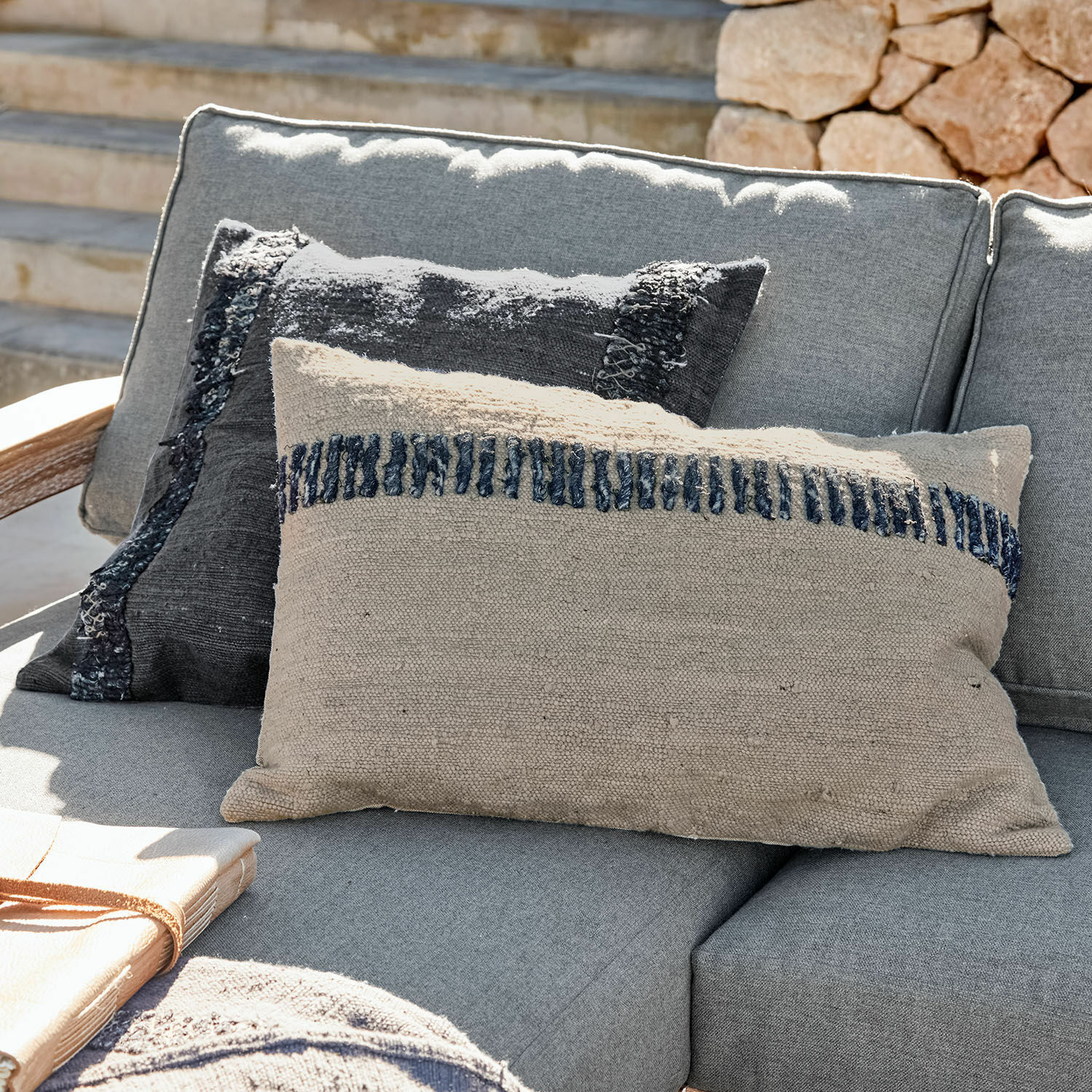 Kissenhülle 2er Set Foix Beige und schwarze dekorative Kissen aus Stoff auf grauem Sofa im Außenbereich, Wohntextilien