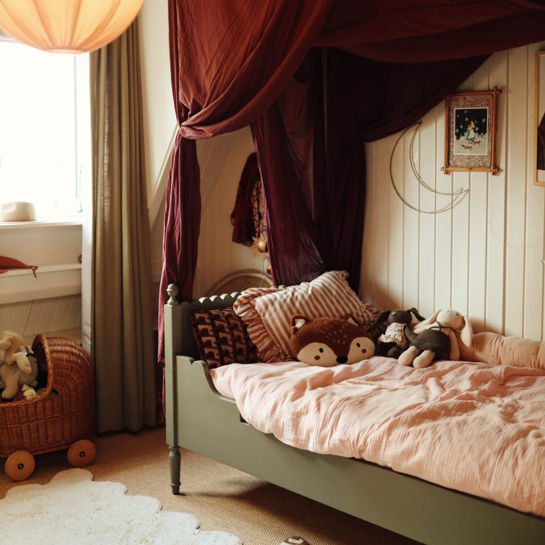 Gemütliches Kinderbett mit grünem Rahmen, rosa Bettwäsche und Plüschtieren in warmem Zimmer