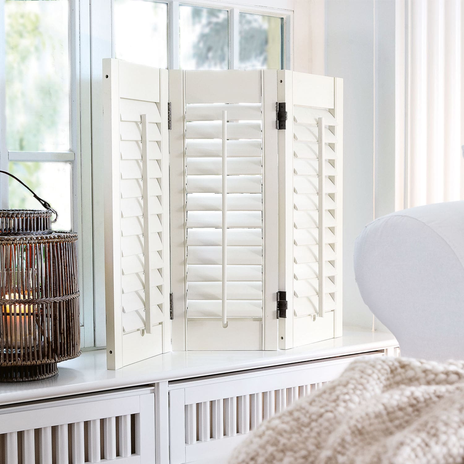 Shutter Ventura Weißer Holz-Paravent mit verstellbaren Lamellen auf Kommode in hellem Wohnzimmer