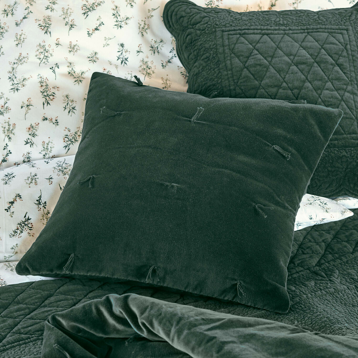 Kissen Orélisse Grünes Samtkissen mit Quasten auf Bett mit gesteppter Decke und floralem Bettbezug