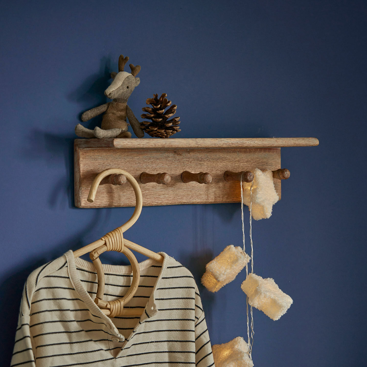 Wandregal Norellan Wandhakenleiste aus Holz mit Rentier-Plüschtier und Lichterkette an blauer Wand