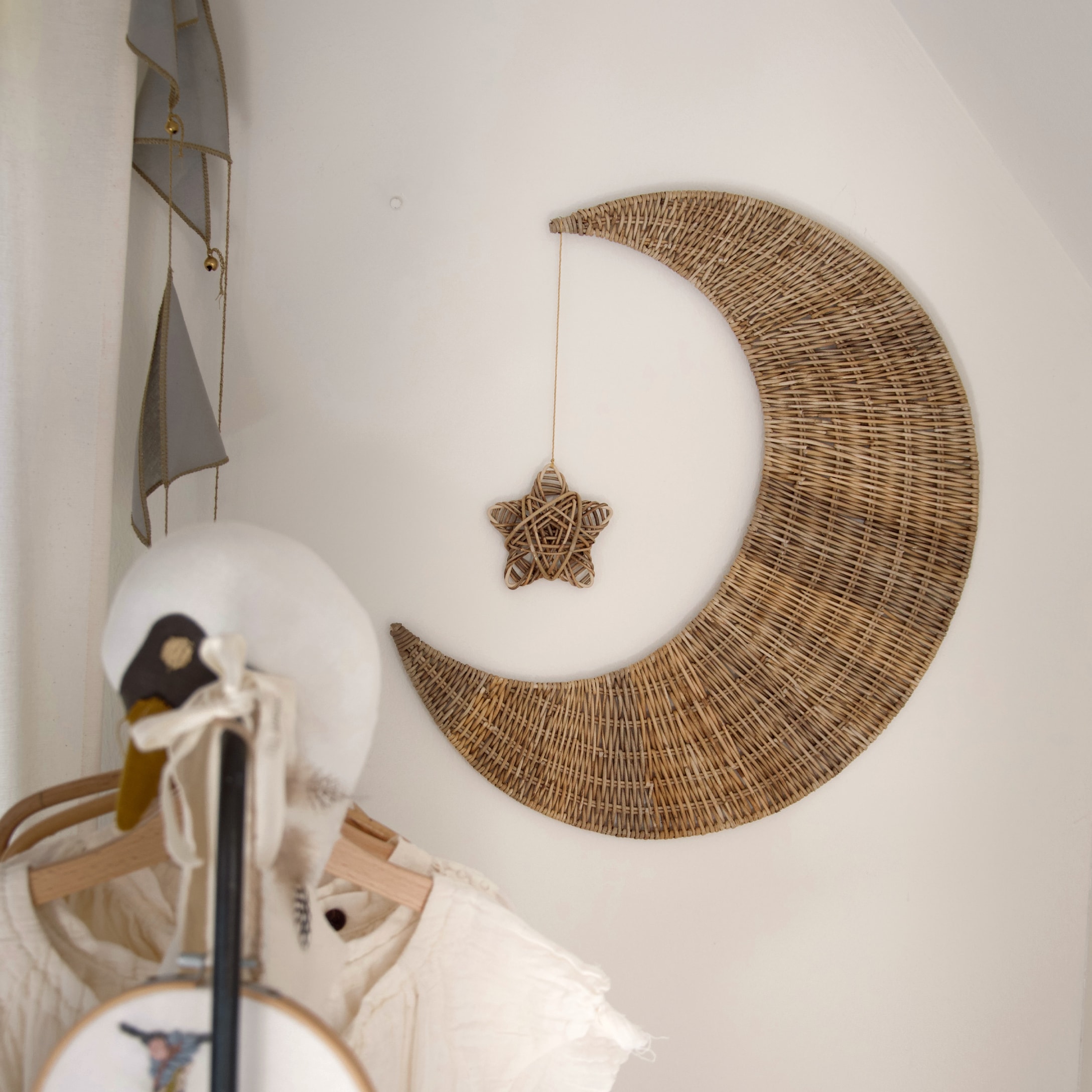 Wanddekoration aus geflochtener Weide in Mondform mit hängendem Stern im Kinderzimmer