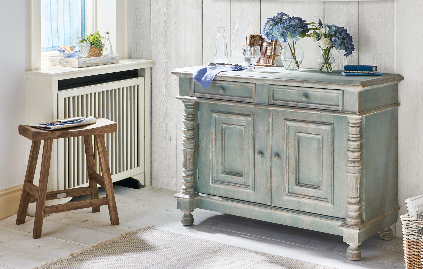 Shabby Chic Kommode aus Holz in grün-grau mit dekorativen Blumen und Glasflaschen