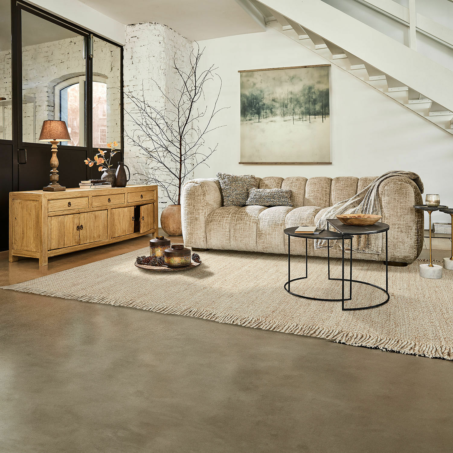 Gemütliches Wohnzimmer mit beigem Stoffsofa, Holzkommode und schwarzen Metall-Couchtischen auf Teppich