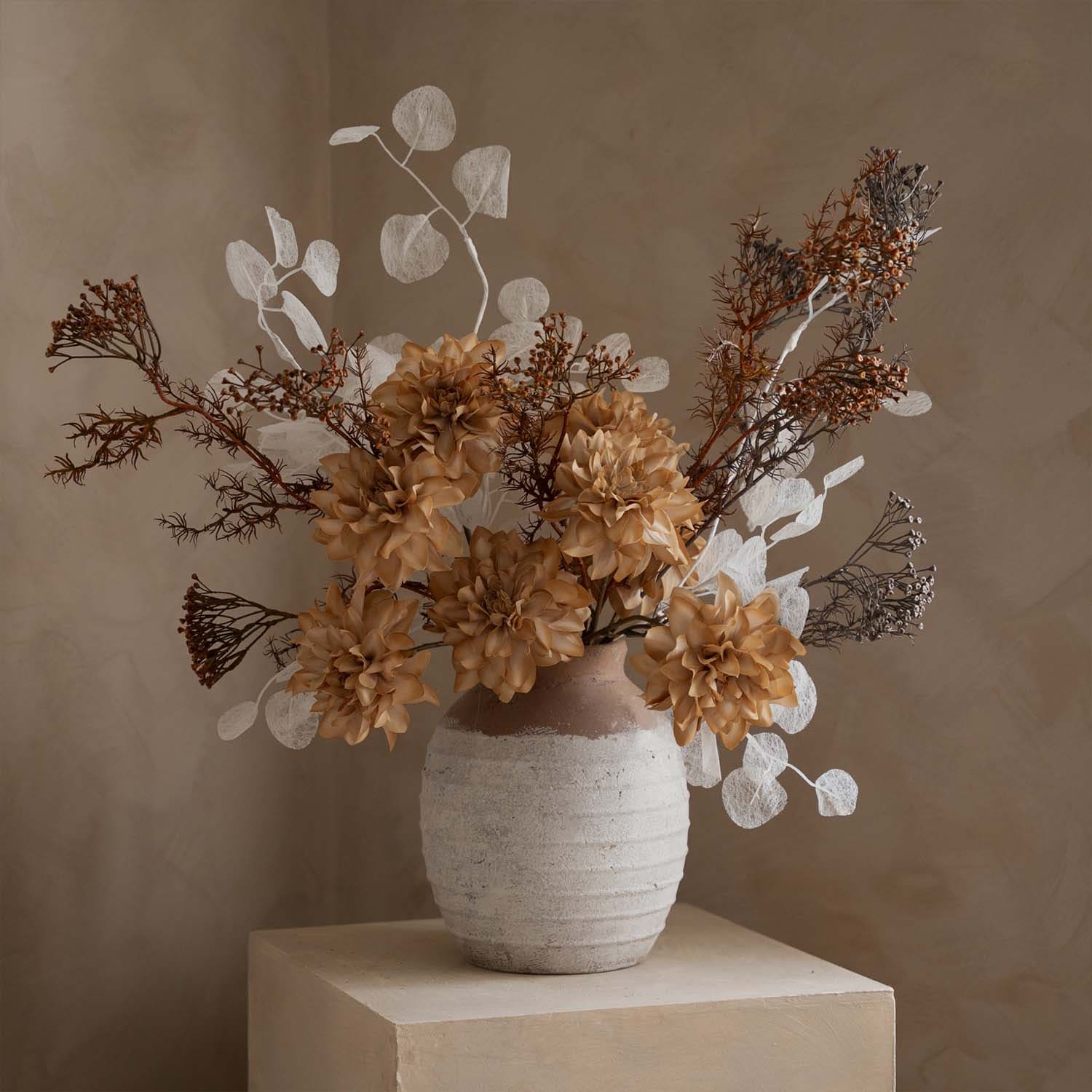 Dekorativer Strauß aus künstlichen Blumen in beige-weißem Keramikvase auf hellem Hintergrund