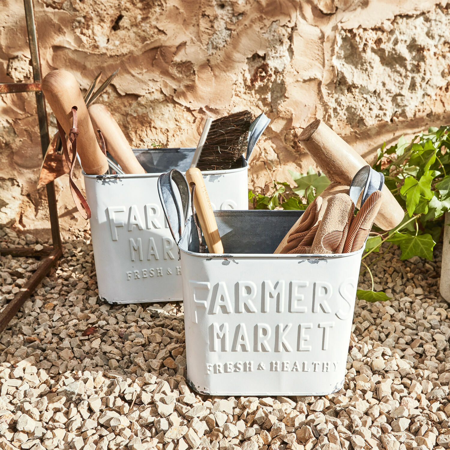 Korb 2er Set Market Weiße Metallbehälter Farmers Market mit Gartengeräten auf kiesigem Boden
