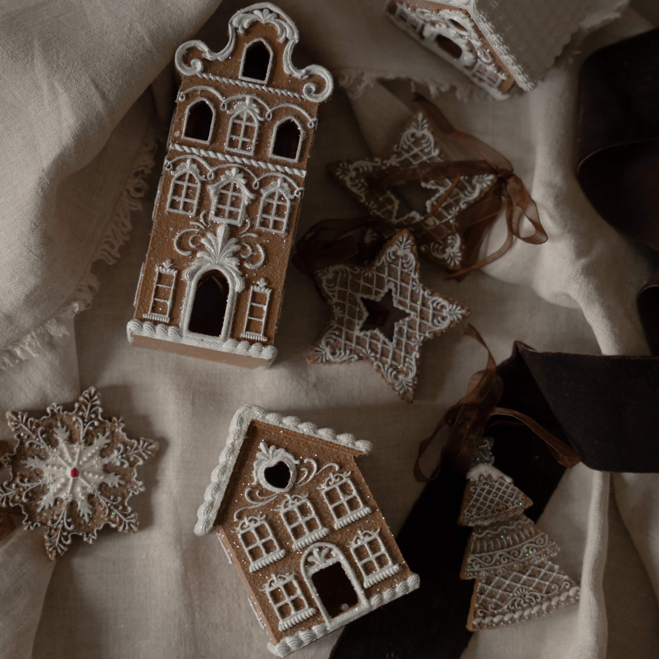 Lebkuchenhäuser und Sterne mit weißer Zuckerglasur auf Leinenstoff, weihnachtliche Dekoration