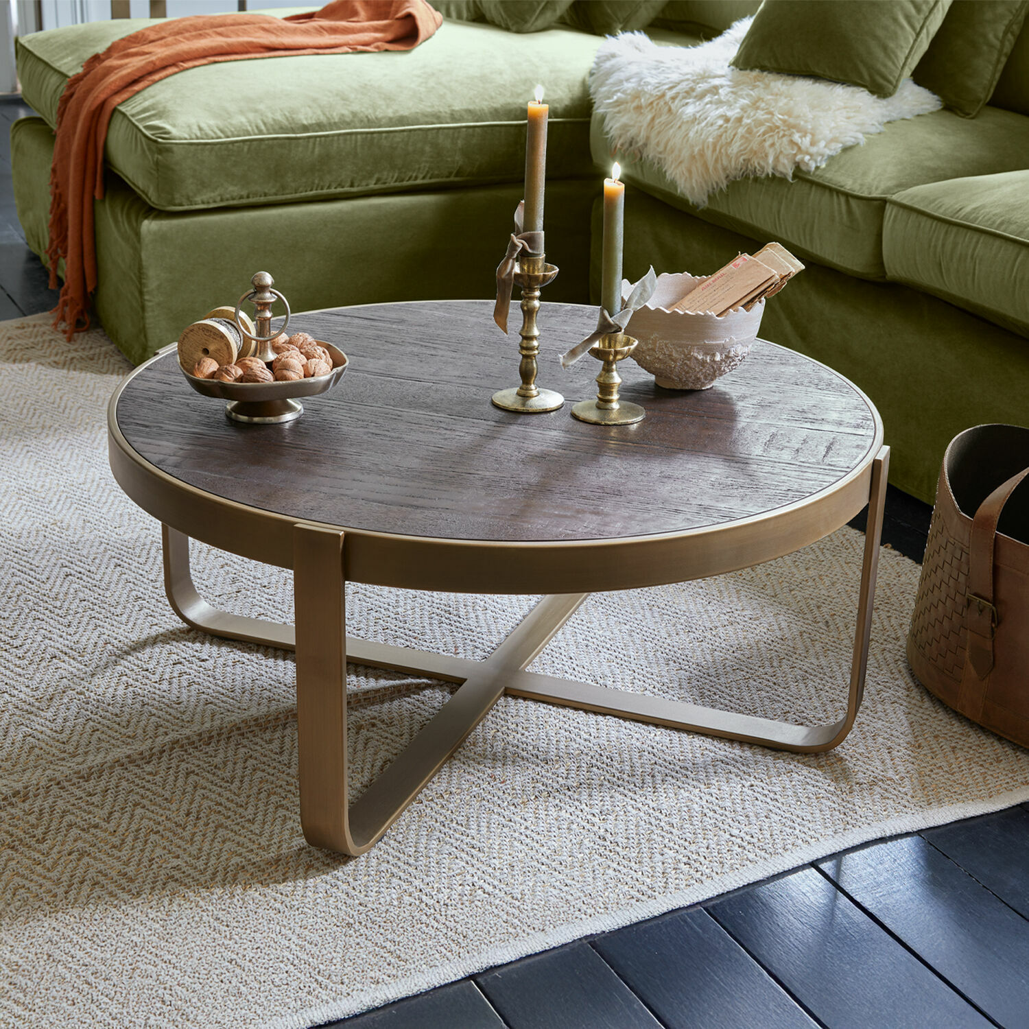 Couchtisch Cranthorpe Runder Couchtisch aus dunklem Holz mit messingfarbenem Metallgestell auf hellem Teppich