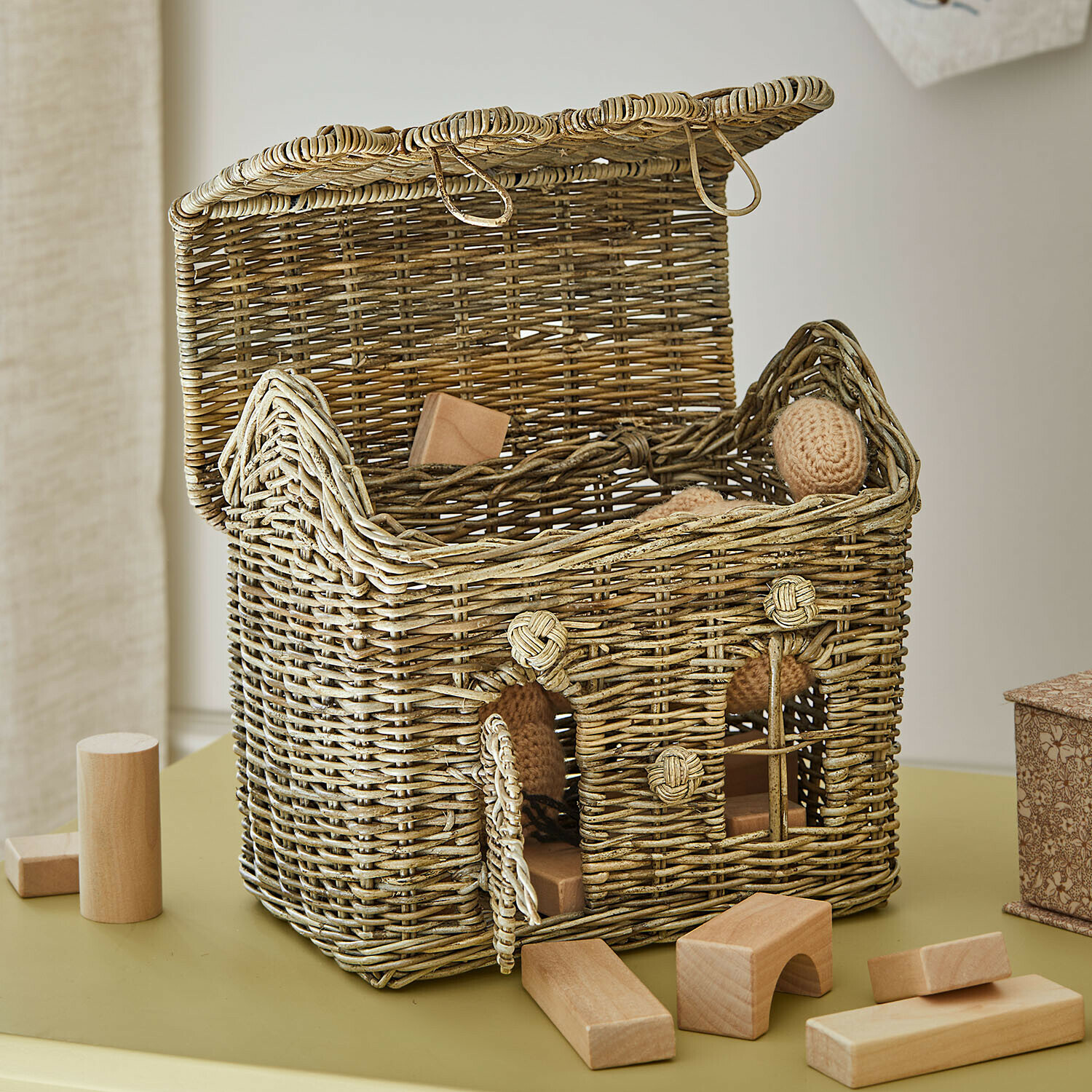Offener Korb aus Weide in Hausform mit Holzbausteinen und Naturfarben-Spielzeug