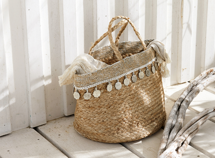 Boho-Korb aus geflochtenem Naturmaterial mit dekorativen Münzen und hellem Schal, Wohnaccessoire.