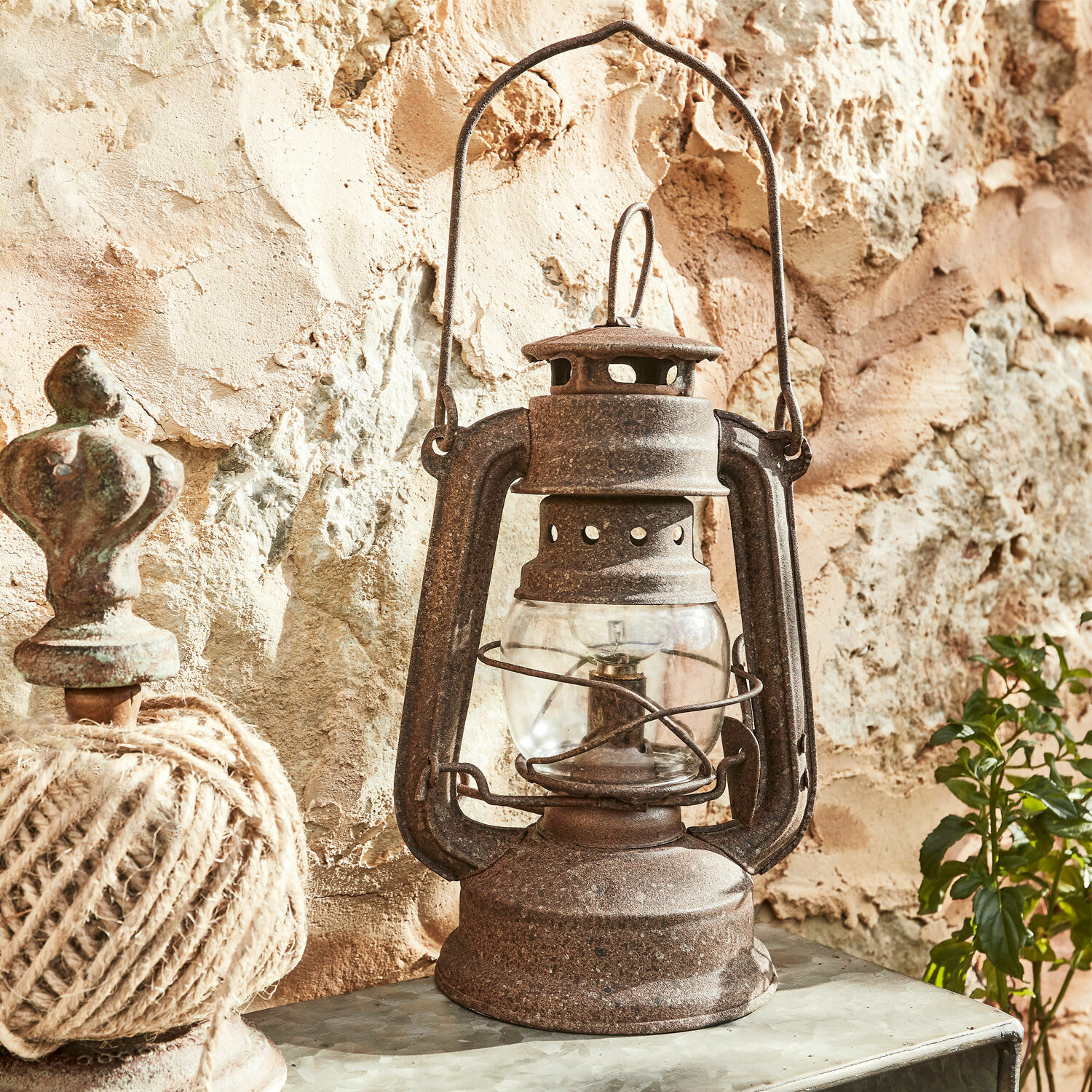 LED-Laterne Oxcroft Rustikale Metall-Öllampe in Rostoptik vor einer Steinwand, Vintage-Dekoration im Landhausstil