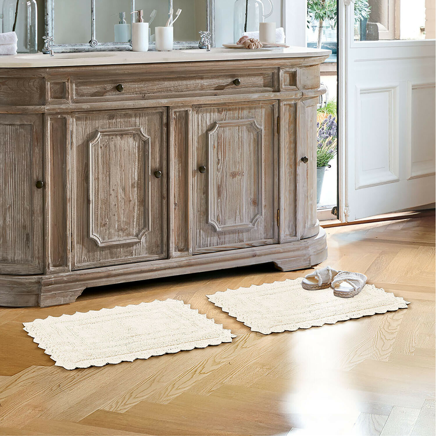 Badematte Yalexir Vintage Holzkommode mit zwei cremefarbenen Teppichen auf hellem Boden in hellem Badezimmer