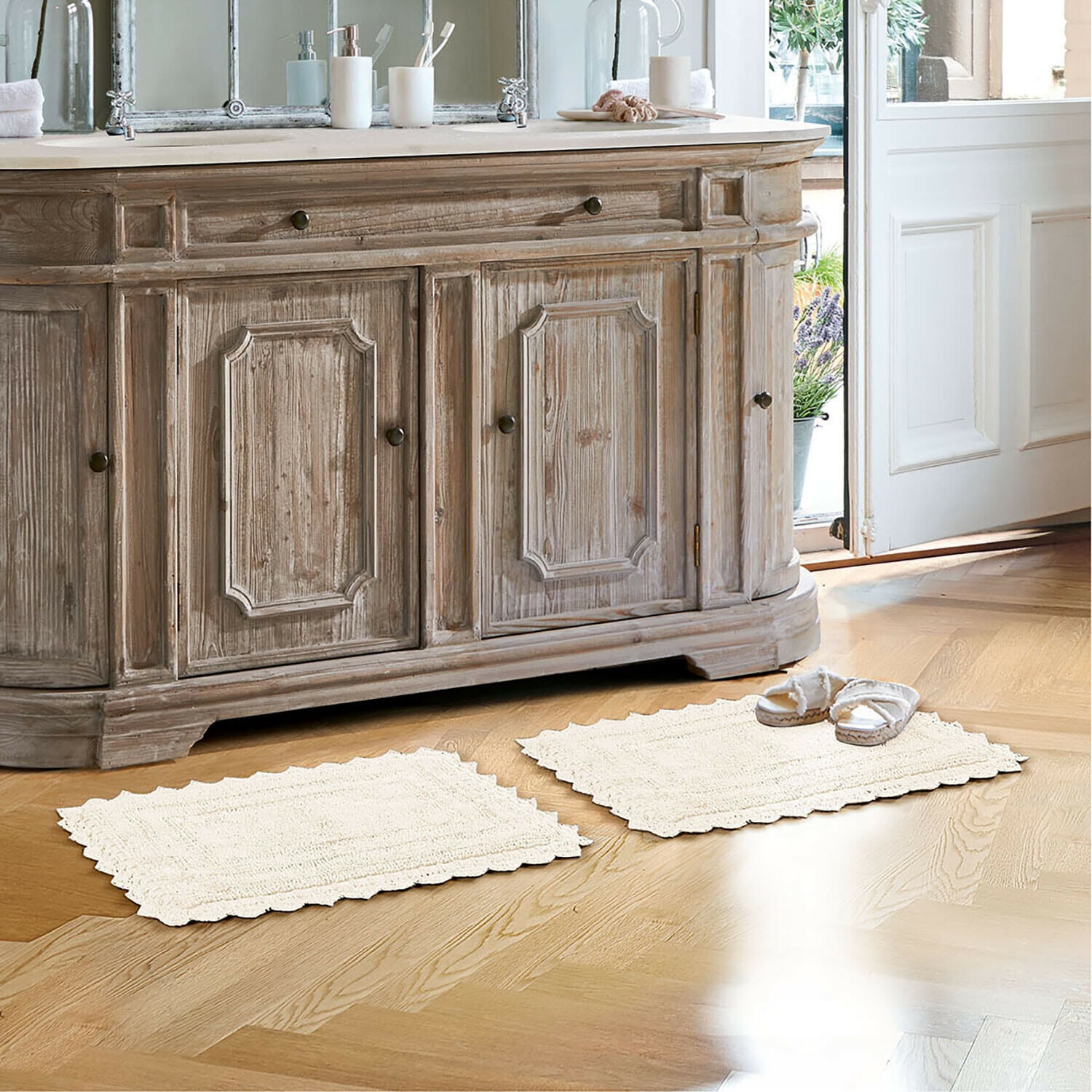 Badematte Yalexir Vintage Holzkommode mit zwei cremefarbenen Teppichen auf hellem Boden in hellem Badezimmer