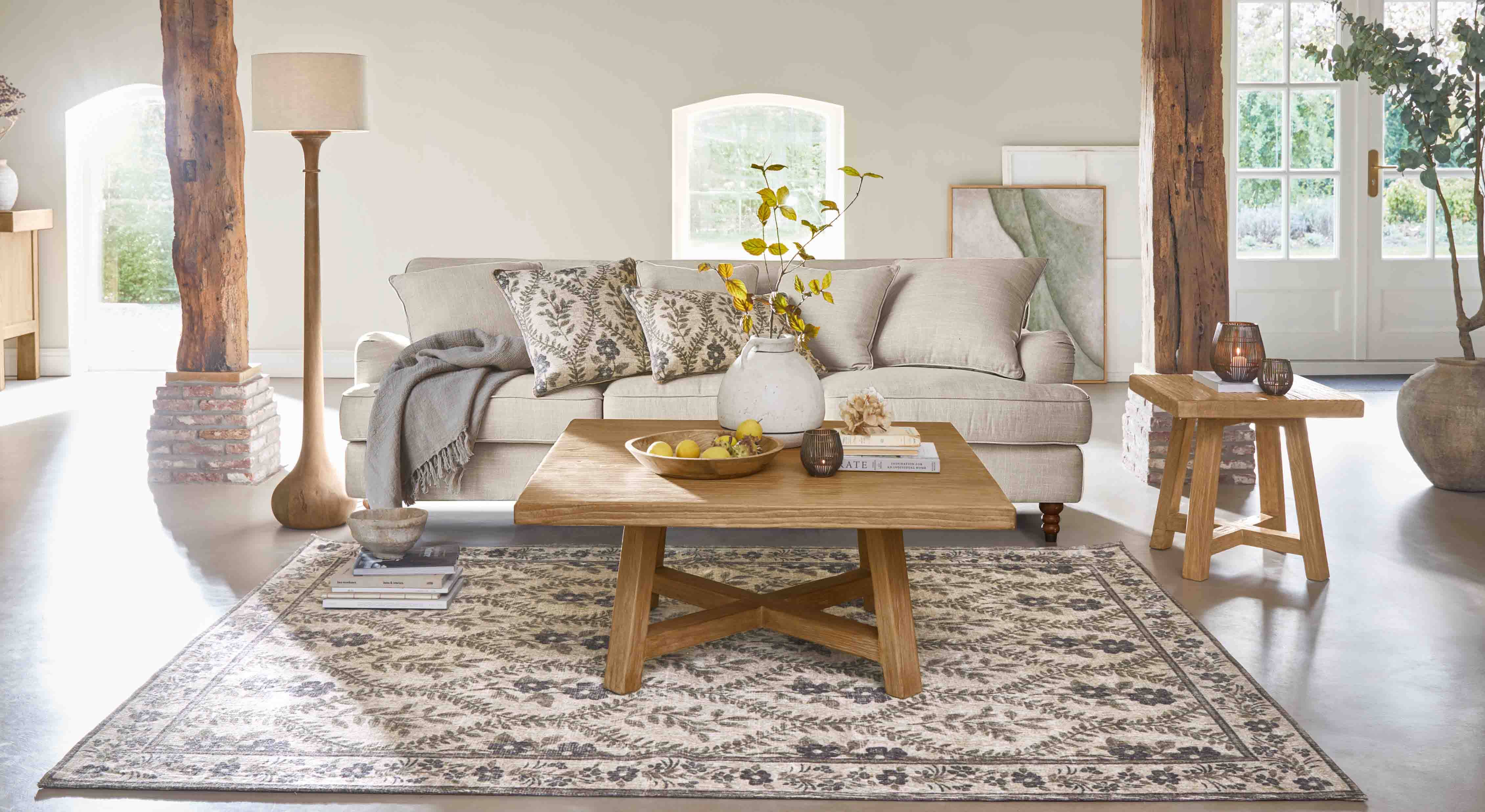 Gemütliches Wohnzimmer mit beigem Sofa, Holztisch und dekorativem Teppich mit Blumenmuster