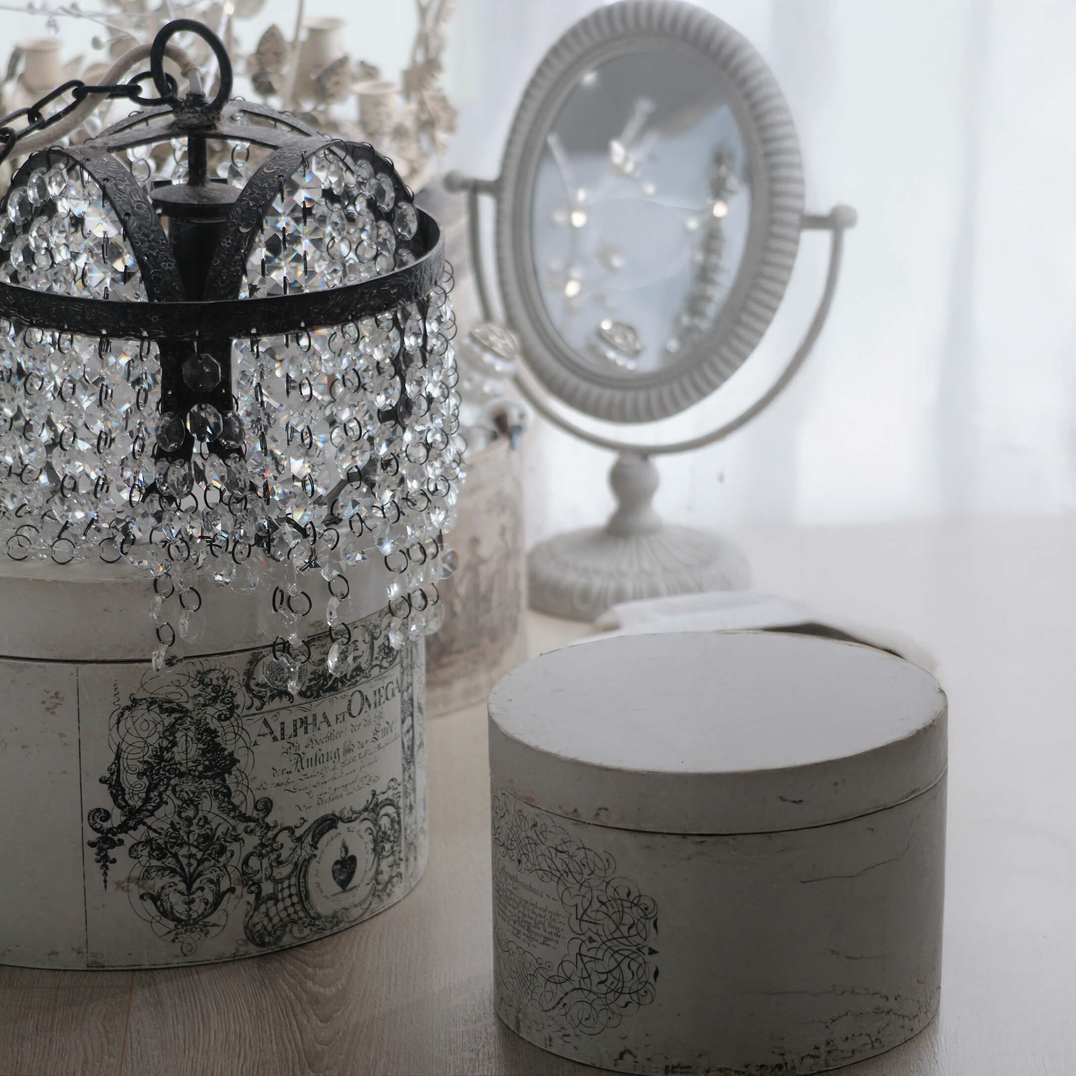 Kristall-Kronleuchter mit schwarzem Metallrahmen auf weißer Vintage-Box mit Ornamenten