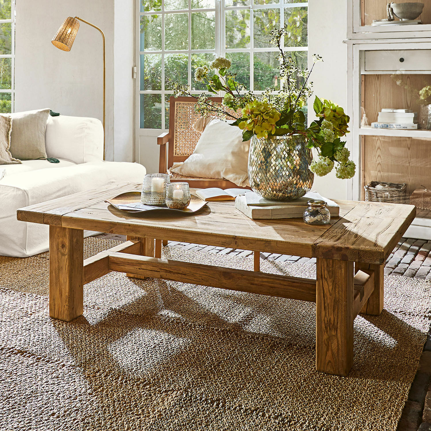 Couchtisch Oteley Holz-Couchtisch in Naturfarbe auf Teppich im hellen Wohnzimmer mit Blumendekor