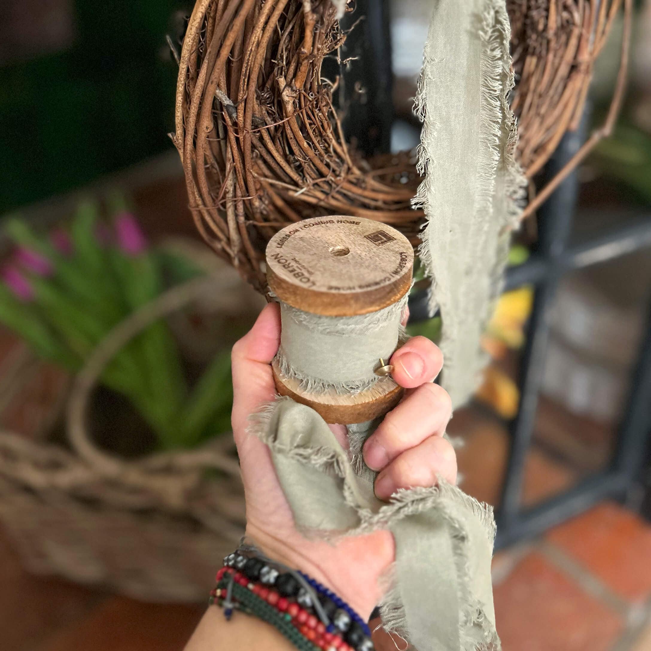 Graues Baumwollband mit ausgefransten Kanten auf Holzspule für Dekoration und Basteln