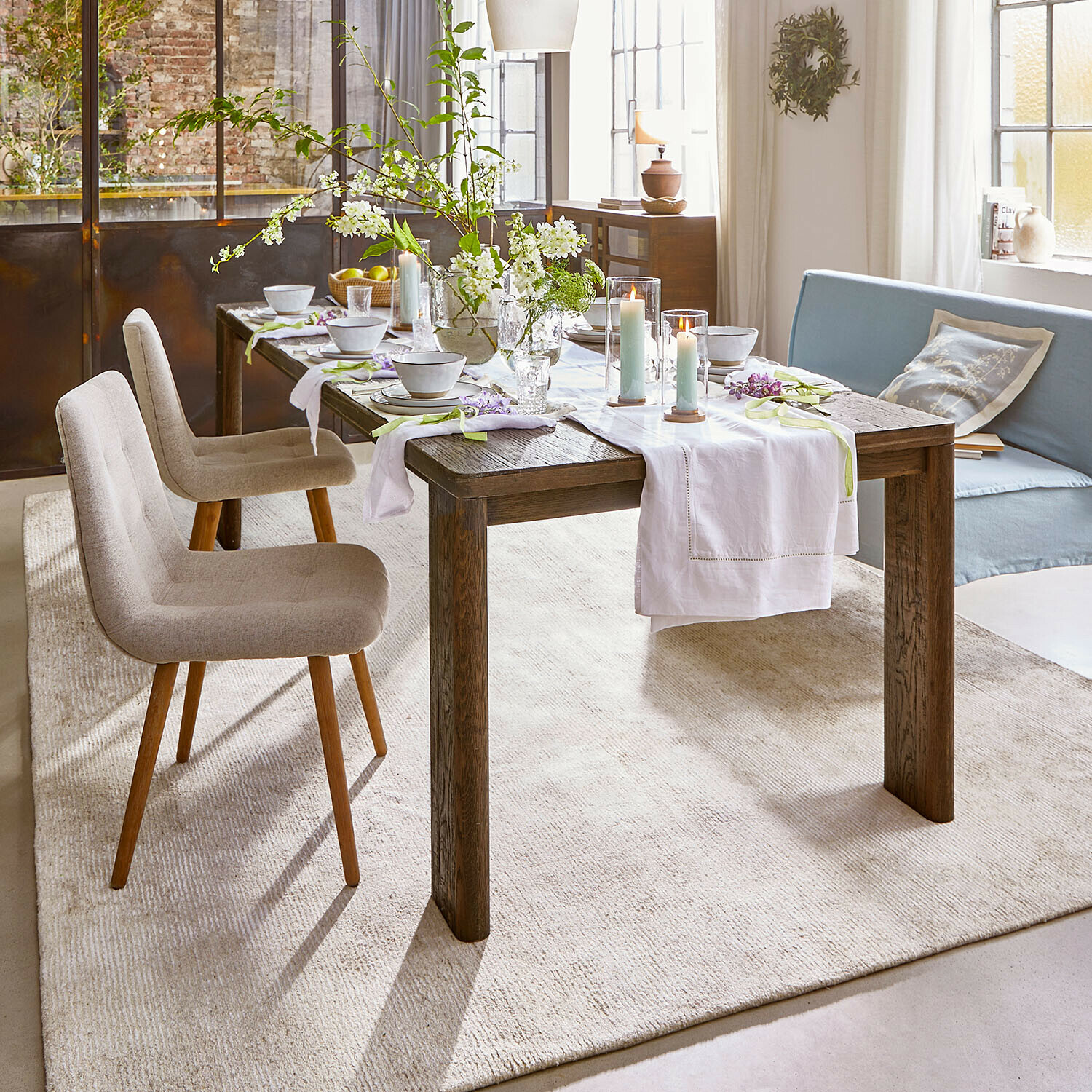 Rustikaler Esstisch aus dunklem Holz mit weißem Läufer und Kerzen in hellem Wohnzimmer
