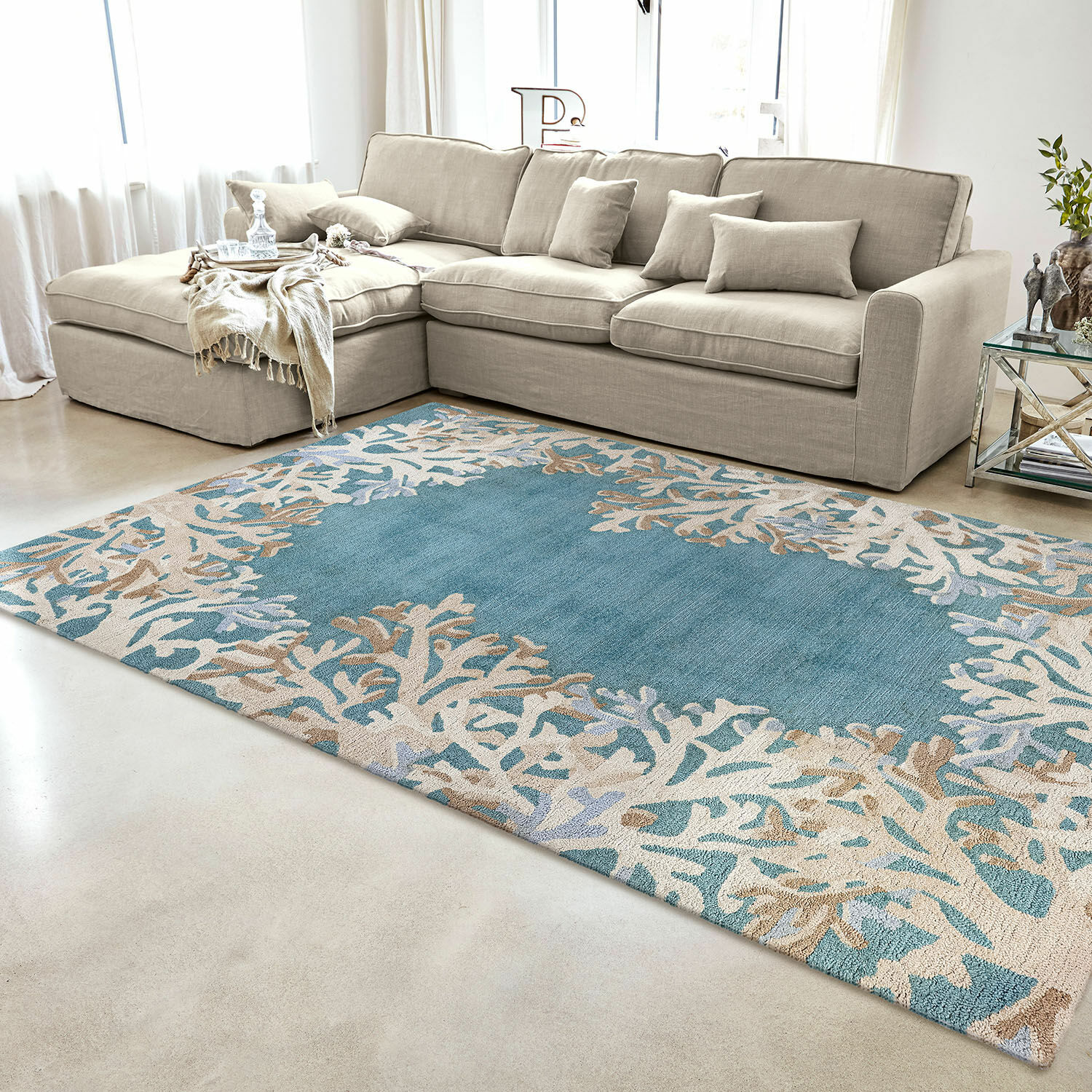 In- & Outdoorteppich Dorlancourt Blau-beiger Teppich mit Korallenmuster im modernen Wohnzimmer mit beigem Sofa und Glastisch