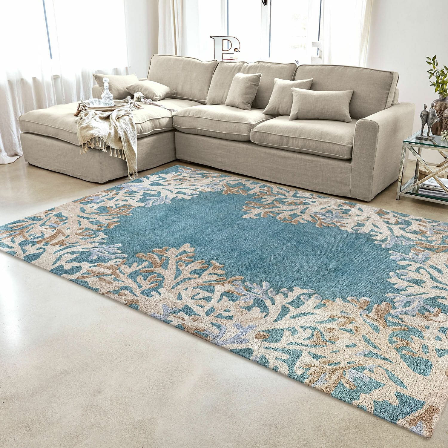In- & Outdoorteppich Dorlancourt Blau-beiger Teppich mit Korallenmuster im modernen Wohnzimmer mit beigem Sofa und Glastisch