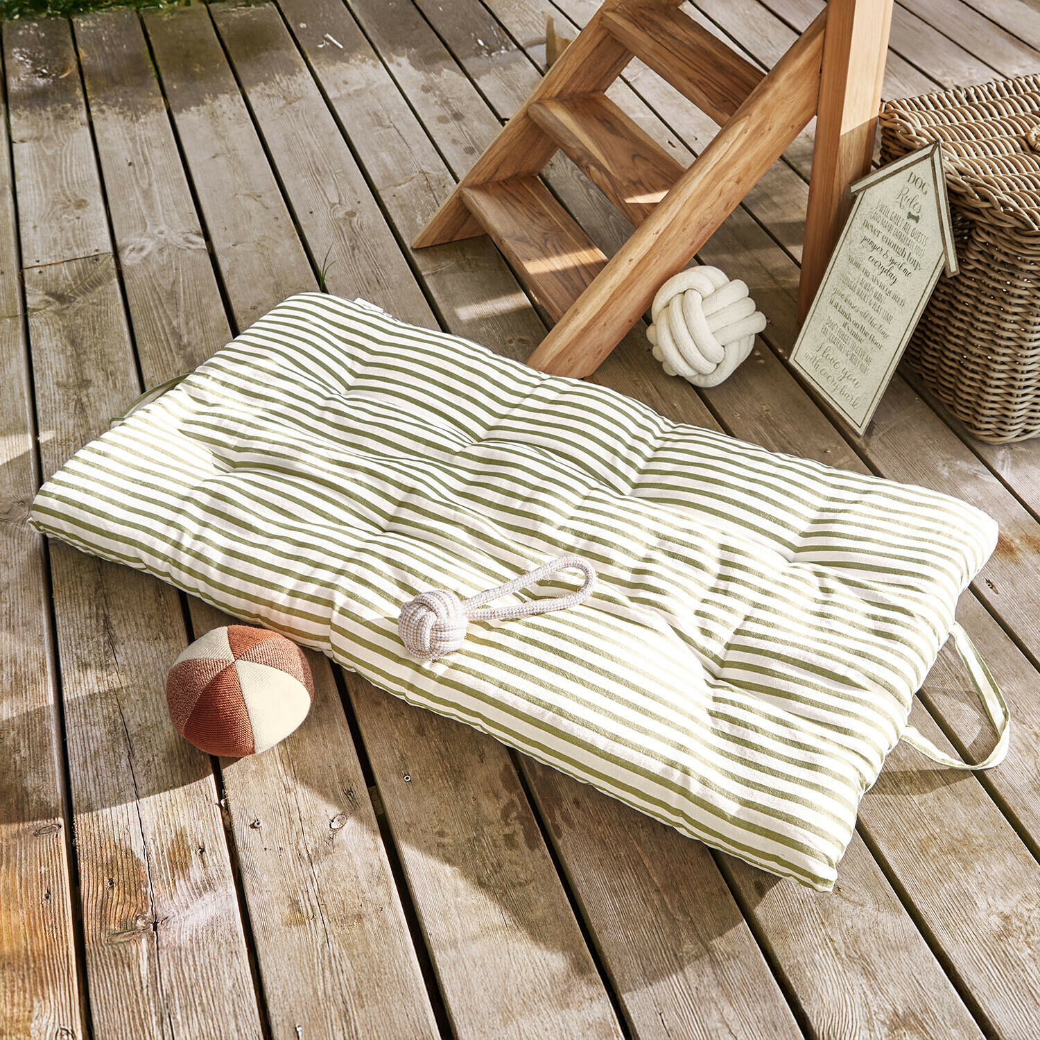 Gepolsterte grün gestreifte Bodenkissen auf Holzterrasse mit Hundespielzeug