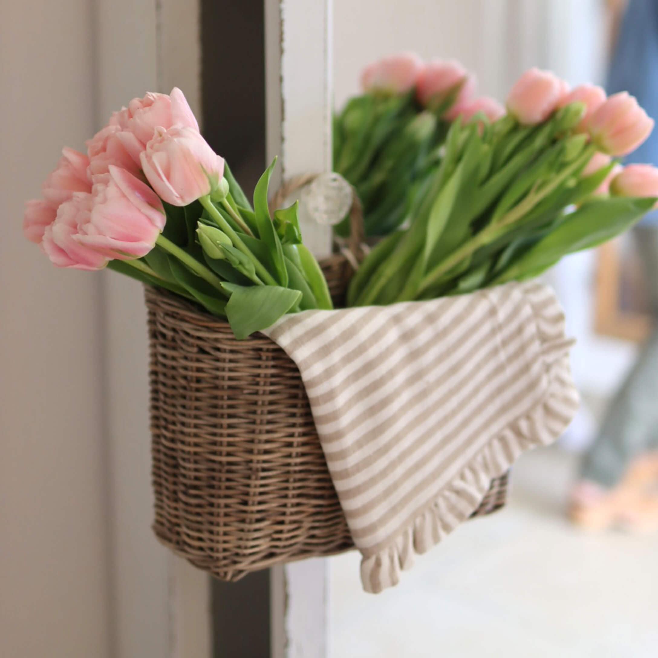 Wikingerkorb mit rosa Tulpen und gestreiftem Baumwolltuch als Wohnaccessoire