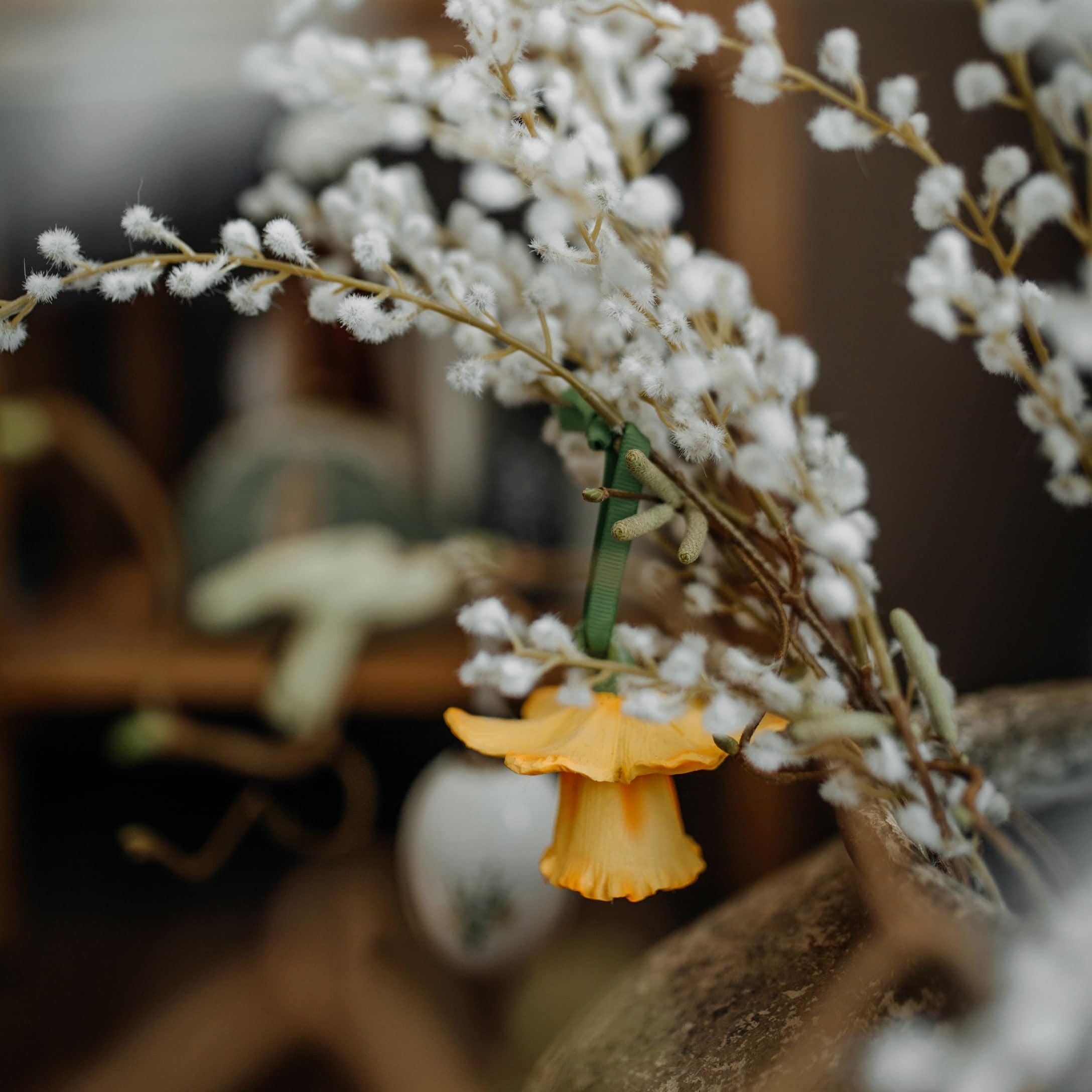 Osterdekoration mit weißen flauschigen Zweigen und gelber Blüte für Wohnräume