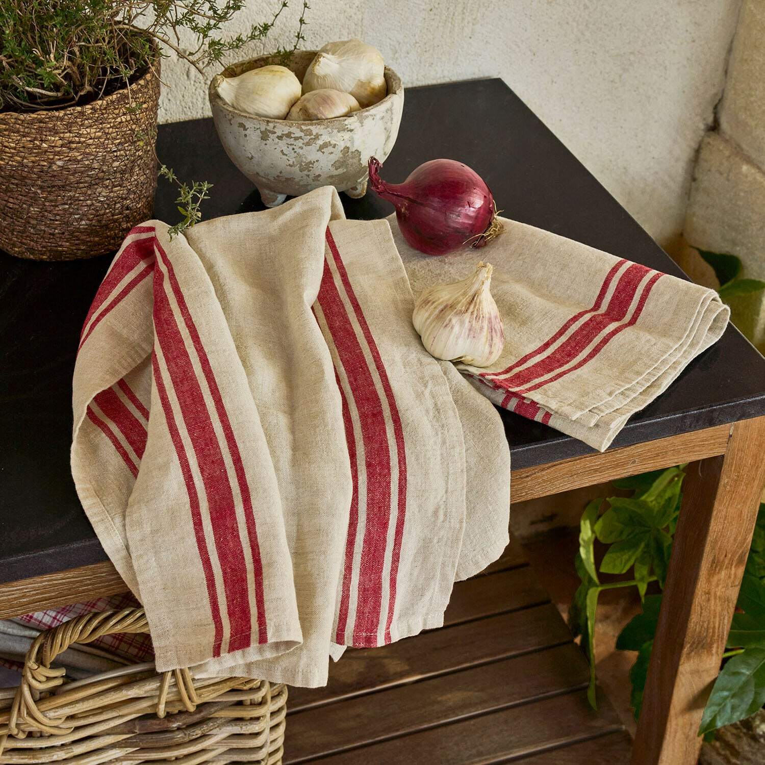 Geschirrtuch 2er Set Norisse Leinen-Küchentuch in Beige mit roten Streifen auf einem Holztisch mit schwarzer Platte
