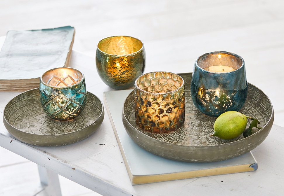 Orientalische Metalltabletts mit gold-blauen dekorativen Kerzenhaltern auf weißem Tisch