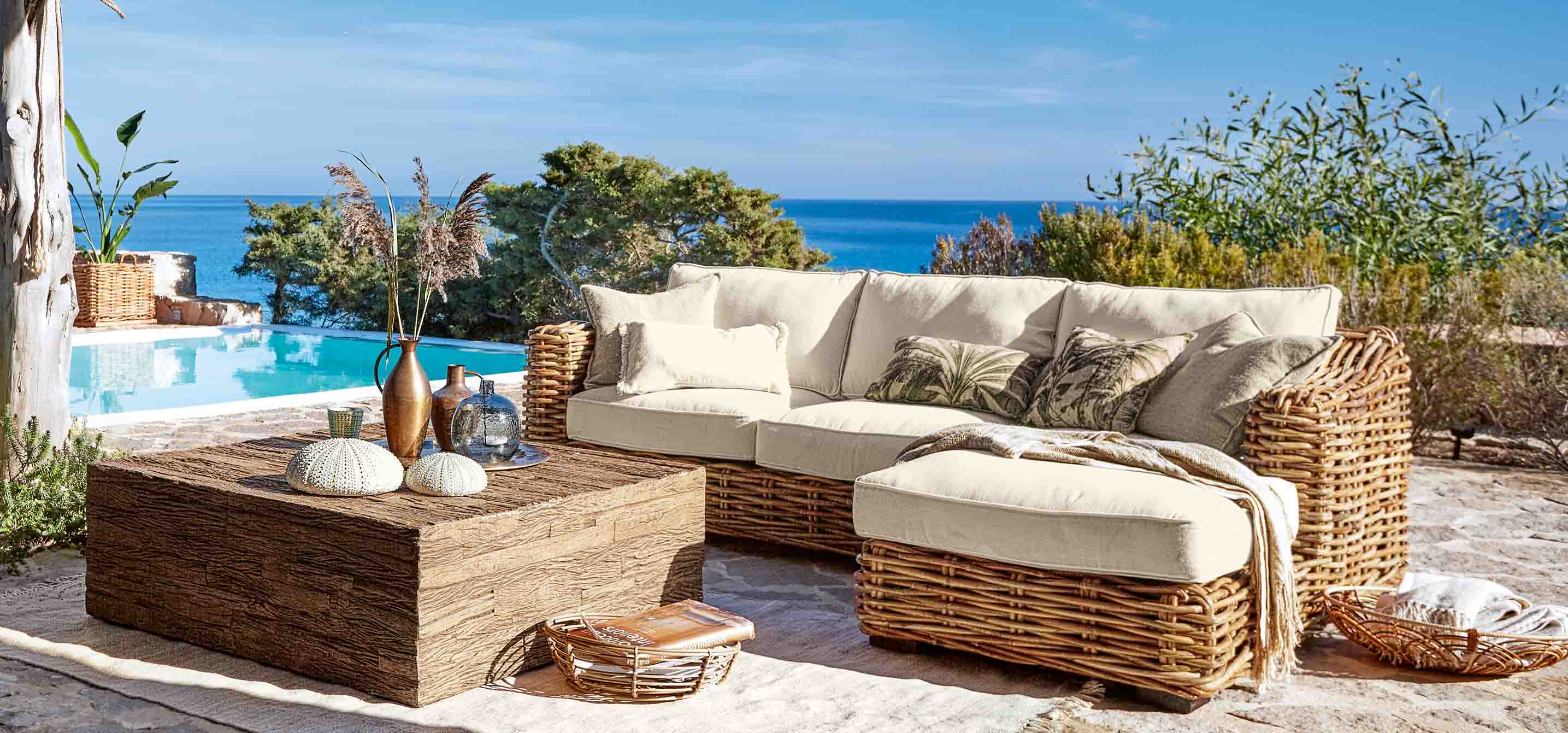 Rattan-Gartenmöbel-Set mit cremefarbenen Polstern am Pool mit Meerblick