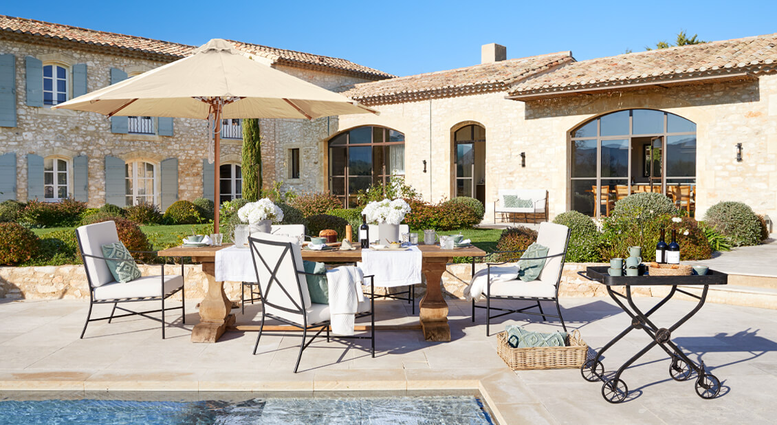 Gartenmöbel-Set mit Holztisch und cremefarbenen Polstern auf Terrasse am Pool