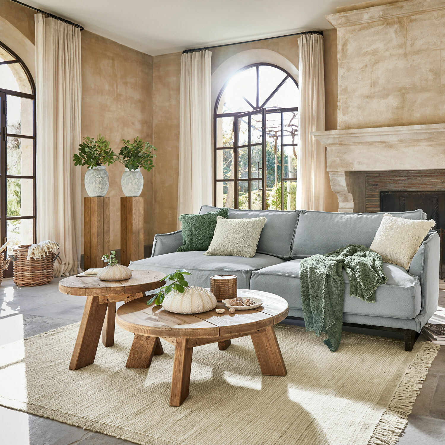 Teppich Placidia Gemütliches Wohnzimmer mit grauem Sofa, rustikalen Holztischen und hellem Naturteppich